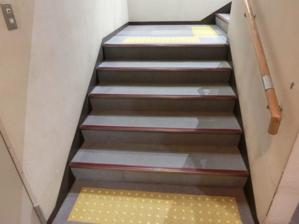 階段の手すりに点字案内、床に点字ブロックがある。